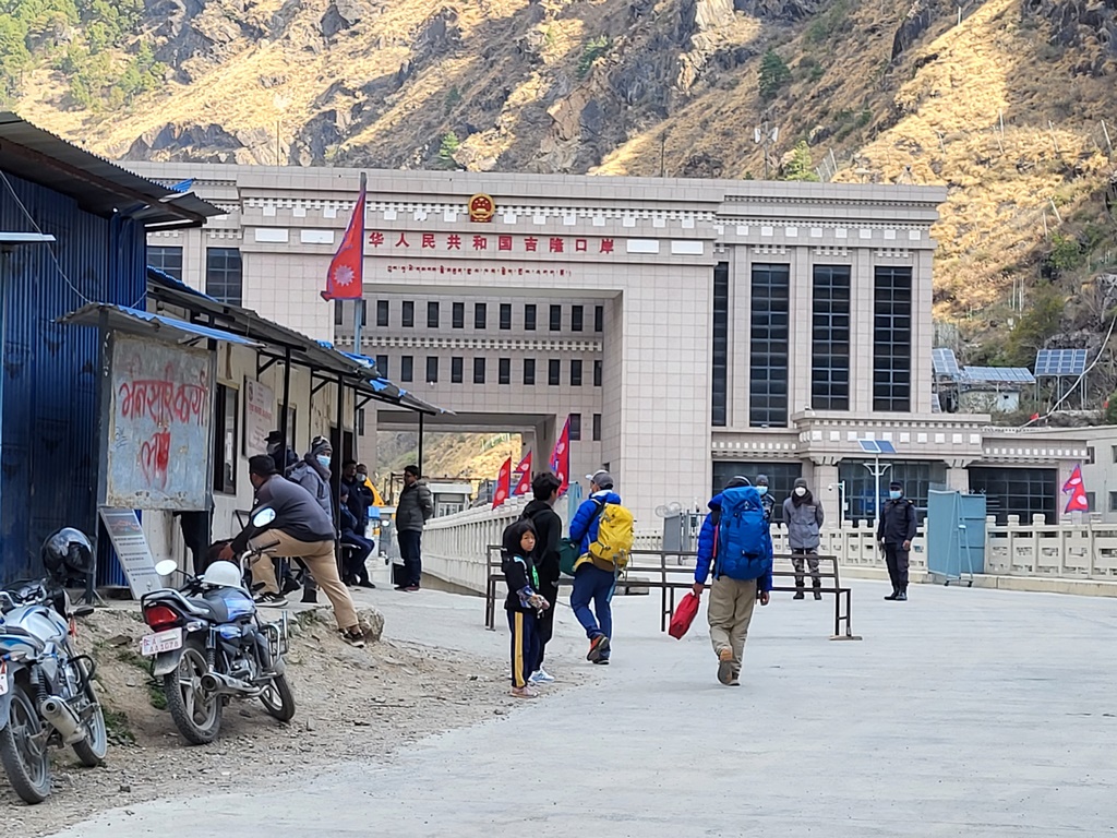 people walking in front of a building with mountains in the background.