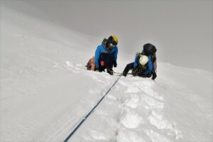 two people climbing up a snowy mountain