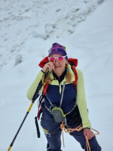 a woman wearing a hat and sunglasses on top of a snowy mountain.