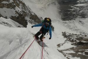 a man climbing huge snowy cliff
