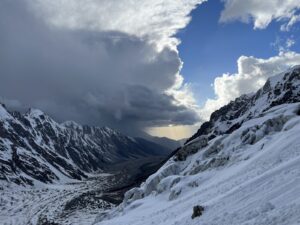huge side of a snowy cliff and cloudy sky above